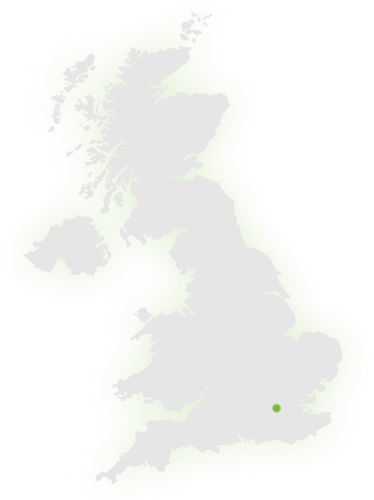 A grey map of the United Kingdom with a single green dot marking a location in the southeast, near London.
