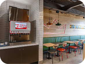 A modern fast-food restaurant interior with a drink dispenser labeled THE CHOICE IS YOURS on the left and a dining area with green booths, wooden tables, colorful chairs, and pendant lights on the right.