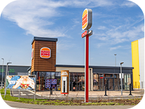 A Burger King fast-food restaurant with a drive-thru, large logo sign, and clear blue sky in the background.